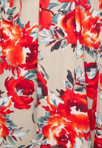 Květinová látka s velkými červenými a oranžovými růžemi a zelenými listy, na béžovém pozadí; jemná textura, živé barvy.