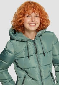 Gevoerde hooded jas in teal, met een ritssluiting, verstelbare trekkoorden en twee zijzakken. Glad, glanzend textuur met gestikte panelen.