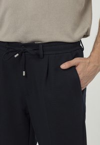 Navyblauwe broeken met een elastische tailleband en verstelbaar koord, met zijzakken en een gestructureerde stofafwerking.