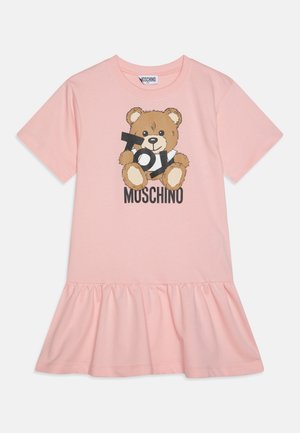 Růžové bavlněné šaty ve tvaru trička s volánovým lemem, s potiskem hnědého medvídka, který drží text "Hračka" a "Moschino", krátké rukávy.