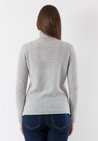 Maglione grigio a collo alto con maniche lunghe, morbido al tatto e dalla vestibilità aderente. Dettagli delle cuciture lungo le spalle e colletto a coste.