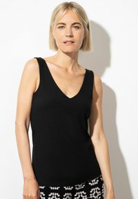 Zwarte mouwloze top met een V-hals ontwerp. Gemaakt van zachte stof, heeft het een aansluitende vorm en minimale details, wat zorgt voor een strakke uitstraling.