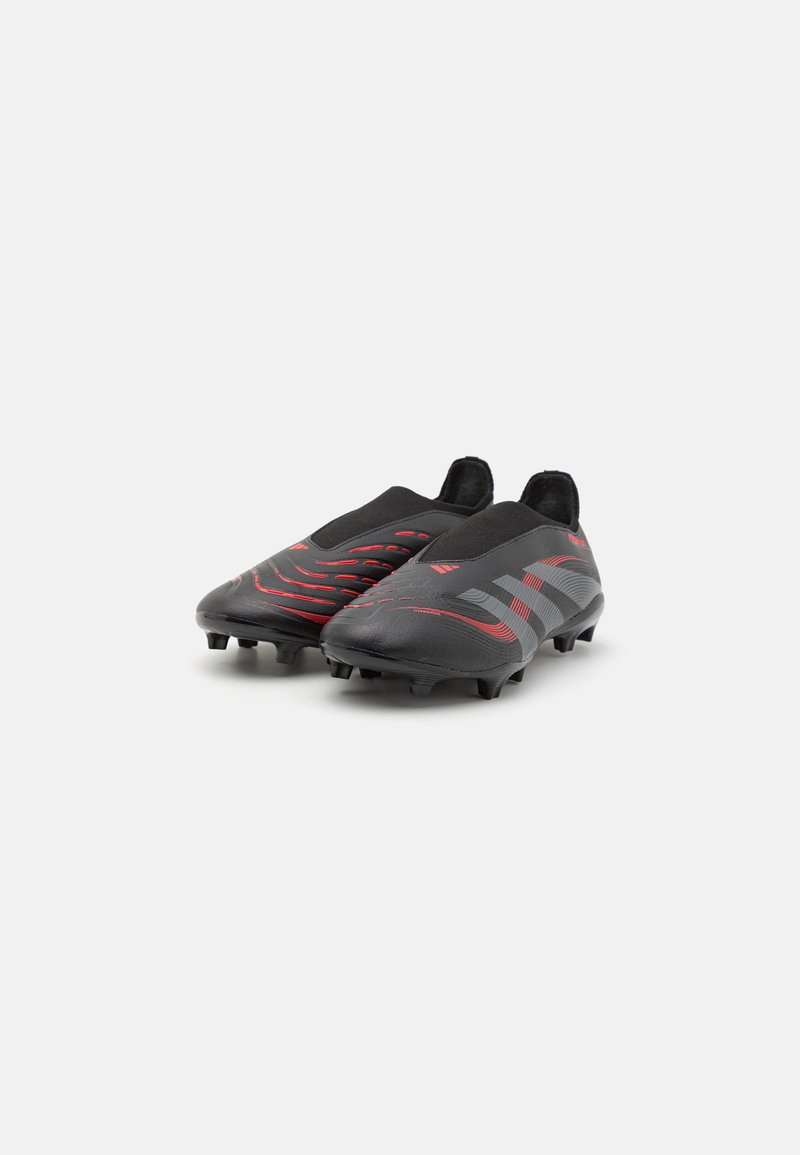 Botas de fútbol negras con patrones en forma de ola rojos y grises, hechas de material sintético, diseño de corte bajo, y clavos de goma para tracción.