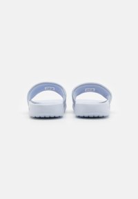Hvide slip-on sandaler med en blød, glat overflade og polstrede remme, der har en struktureret sål for greb og et minimalistisk design.