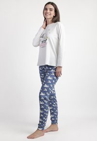 Conjunto de pijama para mujeres que incluye una camiseta blanca de manga larga con estampado de Snoopy y pantalones azul oscuro con patrones de muñecos de nieve y lunares.