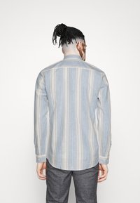 Gestreept overhemd in lichtblauw en beige, met een kraag, gebuttonde manchetten en een rechte zoom. Gemaakt van lichtgewicht stof met een gestructureerde afwerking.