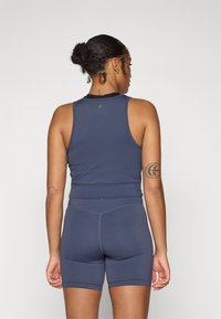Marineblå treningsdrakt som inkluderer en ärmløs topp og høy midje shorts, laget av glatt, elastisk stoff med minimale sømdetaljer.