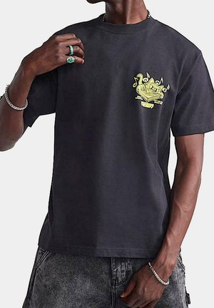 Czarny t-shirt z bawełny z jasnoskrzydłym, żółtym wzorem graficznym po lewej stronie klatki piersiowej. Krótkie rękawy, okrągły dekolt i luźny krój.