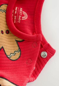 Roter Baumwoll-Strampler für Babys mit gerippter Textur, ausgestattet mit einem Print von Lebkuchenmännern. Enthält Druckknöpfe für ein einfaches Ankleiden.