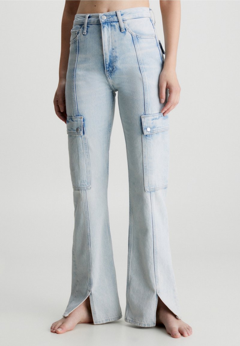 Pantalon cargo en denim bleu clair avec taille haute, jambes évasées, détails de poches et fentes à l'ourlet pour un style et une ventilation accrus.