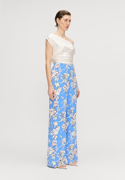 Off-shoulder satin top i elfenben, parret med vidde bukser med blomsterprint i blå baggrund med hvidt og pink blomster mønster.