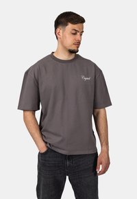 Hedvábný oversized šedý tričko vyrobené z bavlny, s kulatým výstřihem a krátkými rukávy; vyšívané logo "Crystal" na hrudi.