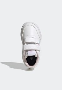 Białe skórzane sneakersy z dwoma regulowanymi paskami na rzepy, zaokrąglonym noskiem i teksturowanymi różowymi akcentami na podeszwie. Minimalistyczny design.