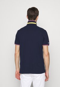 Námořnická polokošile s krátkými rukávy, s límečkem se žlutými a červenými pruhy, jemným logem na rukávu a klasickým střihem.