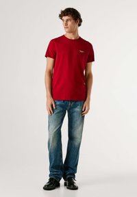 Rood katoenen t-shirt met ronde hals, korte mouwen en een klein logo. Gecombineerd met vervaagde blauwe jeans met rechte pijpen en zwarte schoenen.
