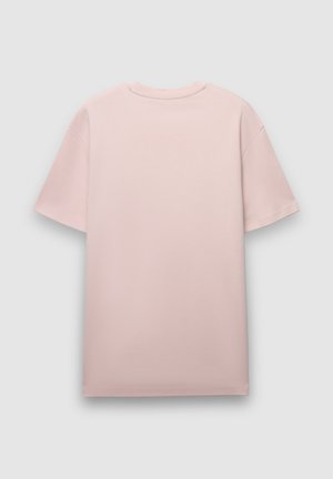 Maglietta oversize rosa con maniche corte, scollo rotondo e texture liscia. Il tessuto appare morbido e leggero, senza motivi visibili.