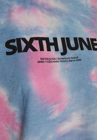 Pozadí vykazuje směs světlých modrých a růžových tónů; výrazný černý text uvádí "SIXTH JUNE" a "Streetstyle značka," což naznačuje identitu značky.