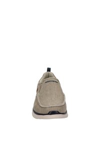 Scarpa slip-on in tela color sabbia chiaro con dettagli in pelle marrone, punta rotonda, collare imbottito e suola bianca. Presenta cuciture decorative e un logo.
