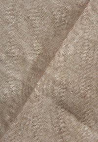 Tessuto di lino in tonalità beige, caratterizzato da una tessitura leggermente testurizzata con sottili variazioni di colore e piccole screziature su tutta la superficie.