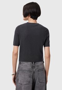 Mørkegrå cropped sweater med korte ærmer, ribbet kant og glat tekstur. Sammen med lysegrå højtaljede jeans med lommer.