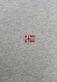 Suéter de punto gris con una pequeña bandera noruega bordada en rojo, blanco y azul, ubicada en el centro del pecho. Textura suave.