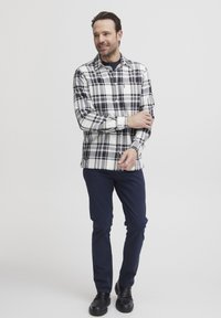 Gestreepte overhemd in wit, zwart en grijs met knoopsluiting kraag, lange mouwen en marineblauwe broek. Soepele stof; zichtbaar merkembleem.