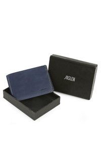 Billetera de cuero azul marino con costuras naranjas, logotipo en relieve y textura suave, presentada en una caja rectangular negra con tapa.