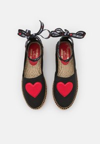 Black canvas espadrilles with large red heart appliqué, braided jute sole, and black ribbon with "LOVE MOSCHINO" text.