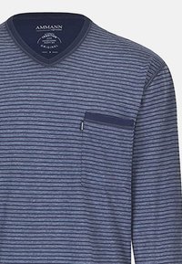 Maglietta a maniche lunghe a righe blu navy con scollo a V e taschino sul petto. Il materiale sembra morbido; le righe sono orizzontali e equidistanti.
