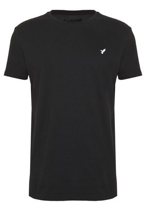 T-shirt noir à manches courtes en coton, avec un col ras du cou et un petit logo d'oiseau blanc sur la partie gauche de la poitrine.