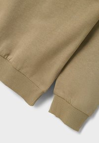 Khaki sweatshirt fabric featuring ribbed cuffs and a smooth texture. The design is simple with no additional patterns or hardware.