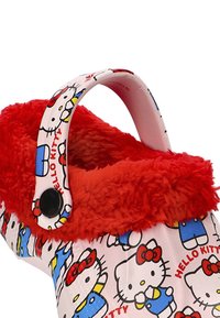 Zuecos de Hello Kitty con un exterior estampado que presenta múltiples caras de Hello Kitty, forro de piel sintética roja y un único cierre de snap negro.