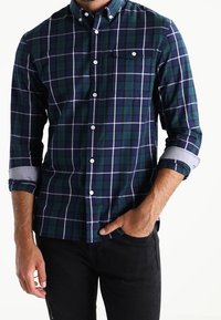 Camicia a quadri blu e verde, con maniche lunghe e polsini a bottone, tasca sul petto e taglio slim. Il tessuto è in cotone testurizzato.