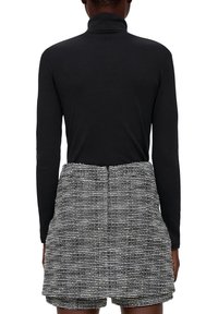Svart långärmad turtleneck som är kombinerad med en texturerad grå och vit randig kjol med fickor och en utsvängd silhuett.