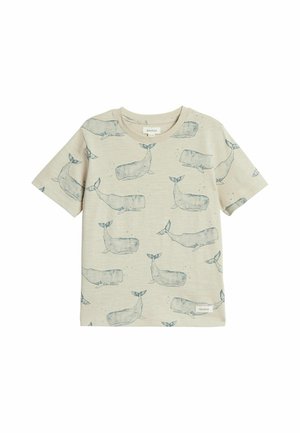 Beżowy t-shirt dla malucha z krótkim rękawem z niebieskimi ilustracjami wielorybów na całej powierzchni i małą materiałową metką z logo w pobliżu brzegu.