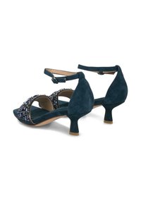 Sandalias de tacón alto de ante en tono teal con correa al tobillo, punta abierta, adornadas con cuentas azules y plateadas, que cuentan con un pequeño tacón cuadrado.