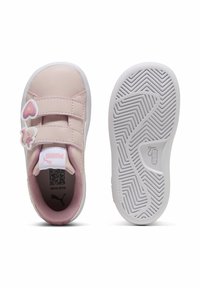 Baskets synthétiques roses avec deux bandes Velcro, accents en forme de cœur et semelles en caoutchouc texturé blanc avec un motif en zigzag.
