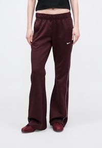 Bordo, visoke atletske hlače s opuštenim krojem, izrađene od glatkog materijala s bijelim bočnim prugama i malim Nike logom.