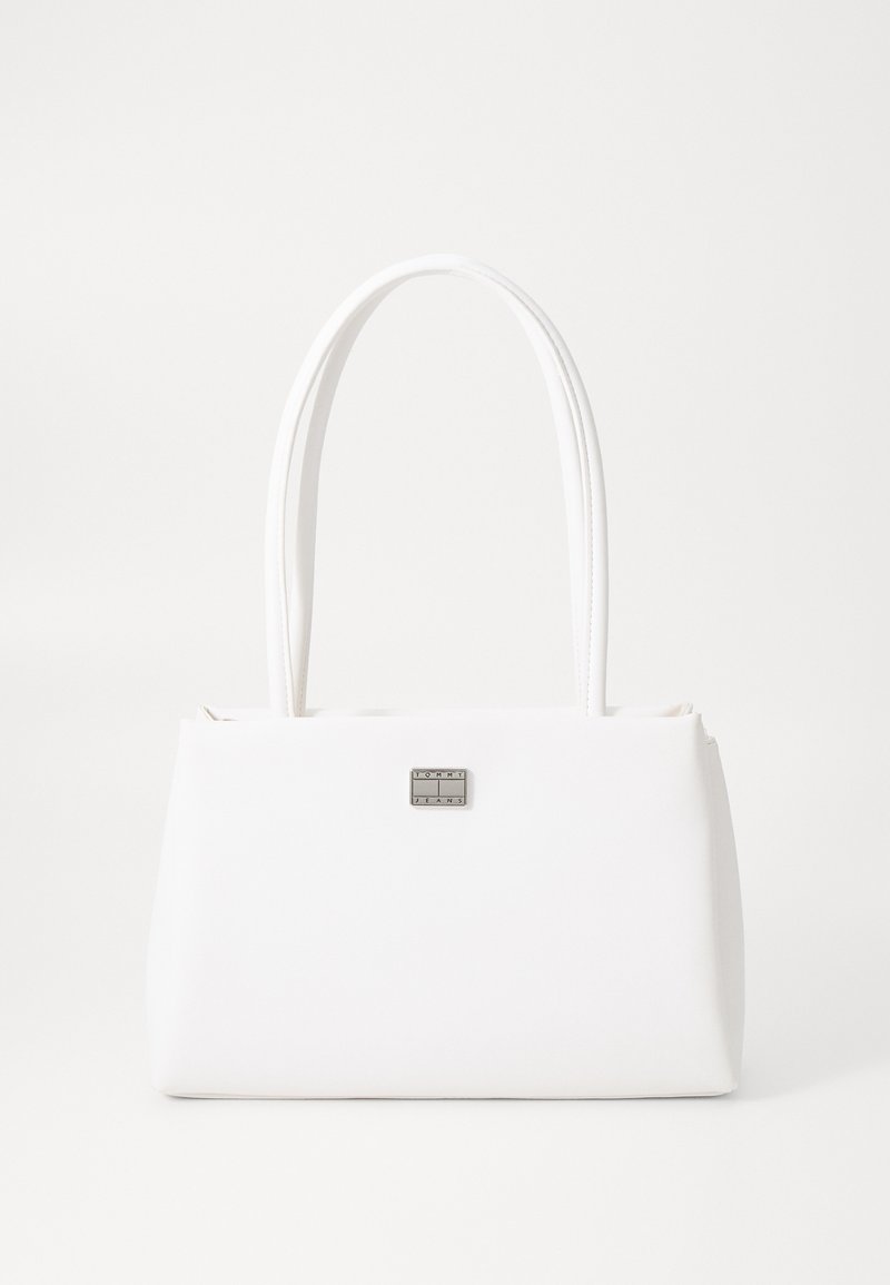 Λευκή τσάντα χειρός από λείο συνθετικό υλικό, με δύο μακριές λαβές, ορθογώνιο σχήμα και ασημί πλάκα λογότυπου μπροστά.