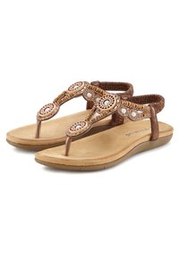 Ruske thongs sandaler med dekorative stropper, der har cirkulære mønstre og perler, blød beige fodseng, tekstureret sål og minimalistisk design.