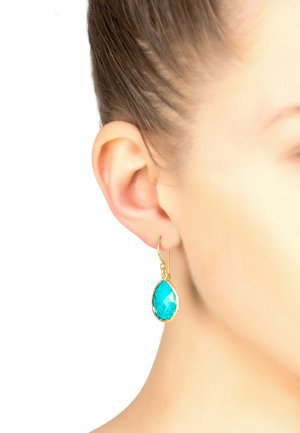 Orecchini a goccia con una pietra di turchese sfaccettata incastonata in metallo tono oro con una superficie liscia. Design leggero, pendente al di sotto del lobo dell'orecchio.