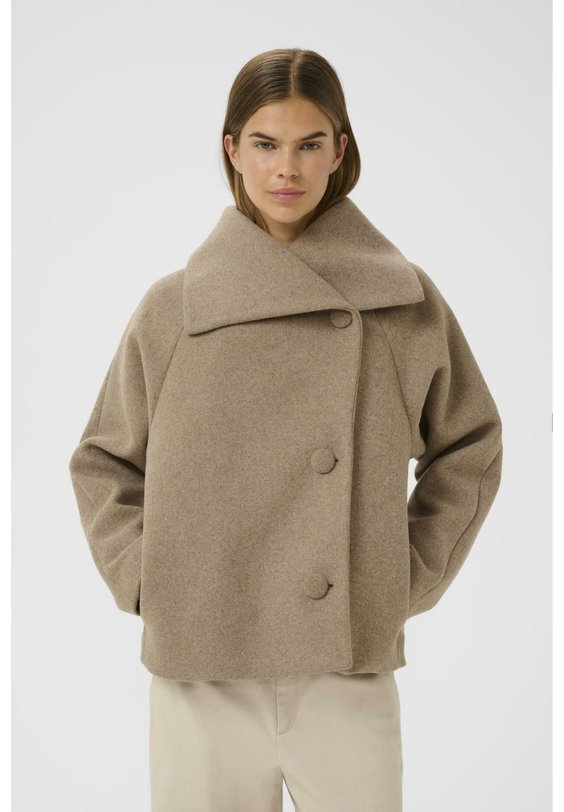 Brown wool blend coat with a high collar, featuring three large buttons and wide sleeves. Soft texture and boxy silhouette.
