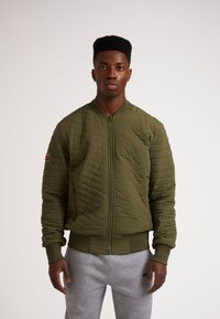 Giubbotto bomber trapuntato in verde oliva, con zip frontale a tutta lunghezza, polsini a costine e una toppa con logo sulla manica. Tessuto liscio e leggero.