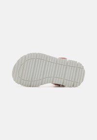 Sneakersåle med en strukturell, ribbet design i hvit gummi, med en rosa aksent øverst, som viser holdbarhet og grep.