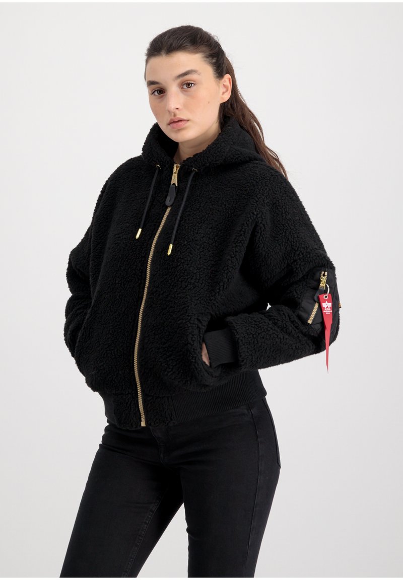 Svart fleece zip-up jacka med huva, guldzip och svarta muddar. Har sidofickor och en liten röd etikett på vänster ärm.