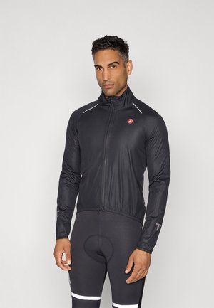 Schwarze Radsportjacke mit hohem Kragen, leichtem Material, Reißverschluss vorne, reflektierenden Akzenten und schmaler Passform, kombiniert mit schwarzen gepolsterten Shorts.