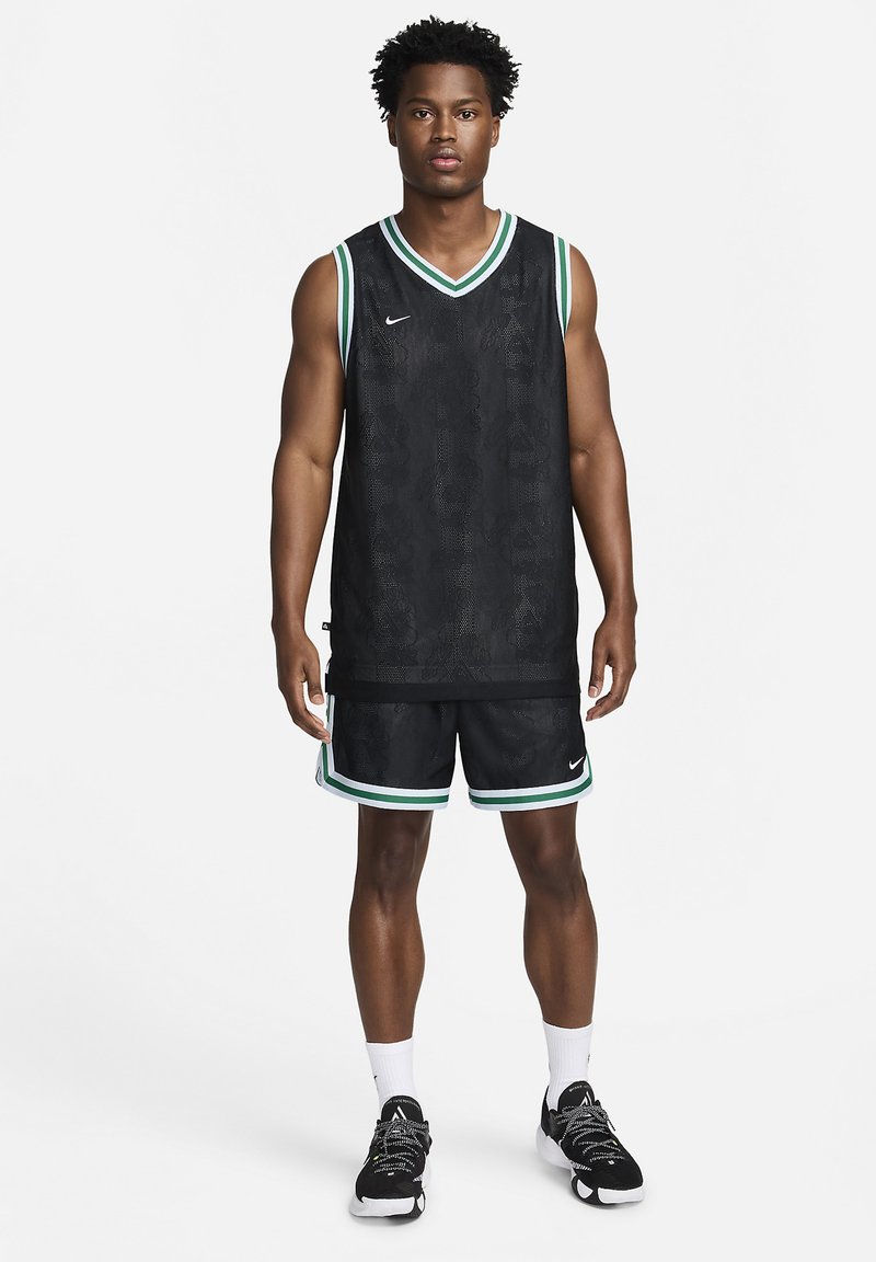 Maillot de basket noir avec un motif texturé, featuring une bordure verte et blanche, associé à un short assorti, le tout par Nike.