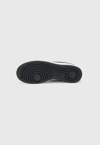 Black rubber shoe sole with circular tread pattern and raised circular accents, featuring a textured surface and defined edges.