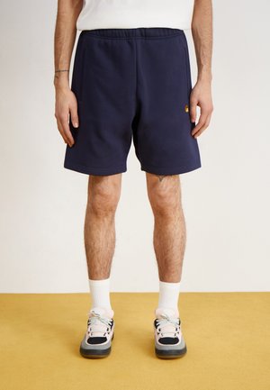 Navy blue shorts made of soft fabric, featuring an elastic waistband and two side pockets. Worn with white socks and multicolored sneakers.
