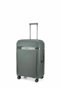 Valise rigide grise avec une finition texturée, poignée rétractable et quatre roues pour la mobilité. Dispose d'un logo à l'avant et d'une fermeture éclair.